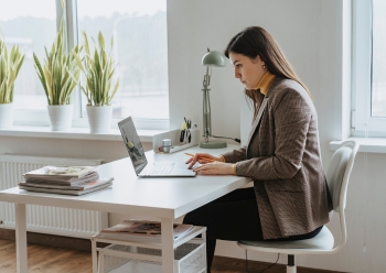 A woman in professional business attire concentrates on her work