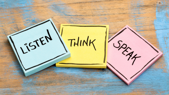 Sticky notes reading Listen, Think, Speak placed on a wooden table, representing thoughtful communication and idea sharing
