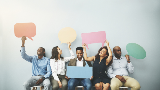 Diverse group of professionals holding colorful speech bubbles, symbolizing open communication and idea exchange in the workplace